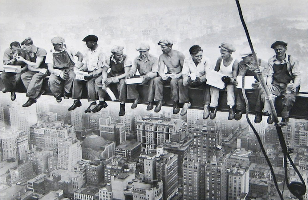 Workers eating lunch on a beam.